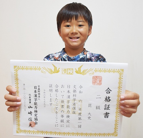 合格証書を手に笑顔の昆くん