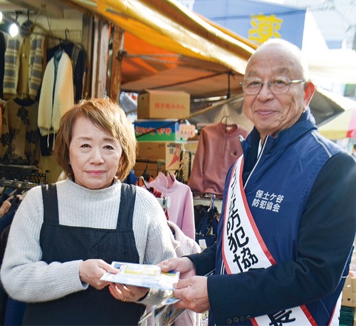 商店の従業員に啓発物を手渡す堀会長（右）