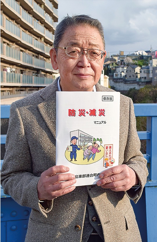 完成したマニュアルを手にする田中会長