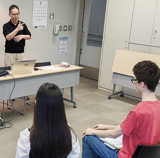 手話講座であいさつする市聴覚障害者協会の小島理事長（左奥）