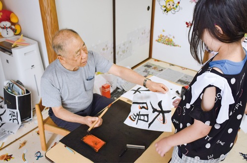 子どもが書いた字を添削する榎本さん（左）