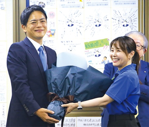 当選確実が報じられ花束を受け取る山中氏（８月３日、中区）
