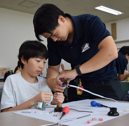 電気工事士体験をする子ども（左）
