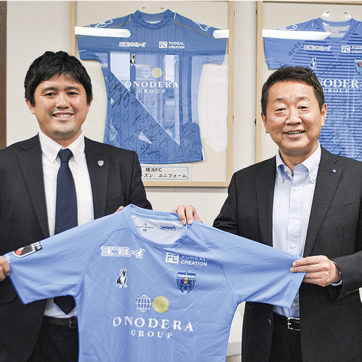 木村ＣＯＯ（左）から贈られたユニフォームを手にする出口区長（右）