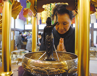 参加者らは香ばしい甘茶を釈迦像にかけ祝った