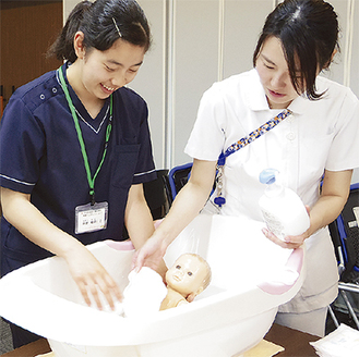 看護師の指導のもと、実際の道具を使って沐浴の流れを体験する参加者＝同院提供