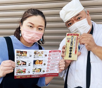 「はらぺこ道中手形」と題し、各店紹介の台紙を持つ発案者の梶さん（右）と参加店のとと屋・永井寛子さん