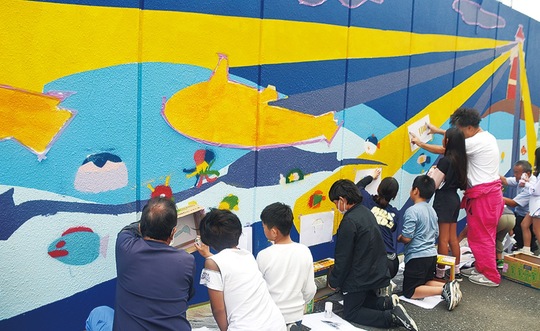 実行委と協力して壁画を制作する児童たち