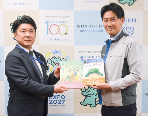 絵本を手渡す日産の古川さん＝右