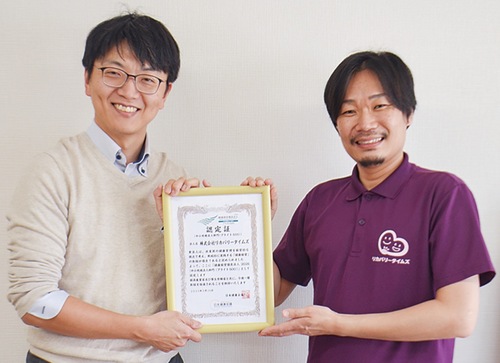 認定証を手に喜ぶ石田さん（左）とスタッフ