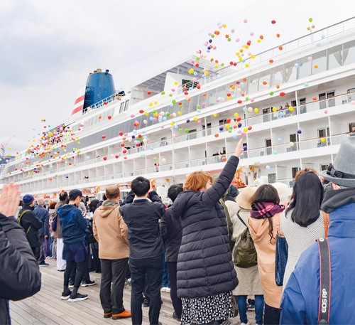 手を振り出港を見送る人々