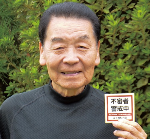 ステッカーを手にする黒川会長