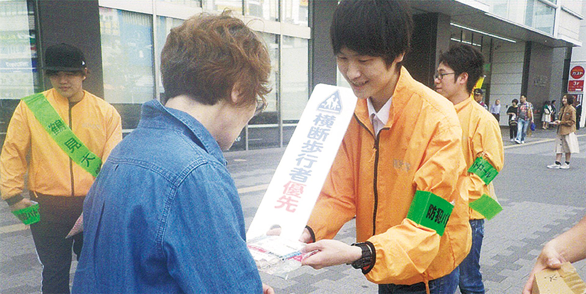 啓発物を配る学生ら