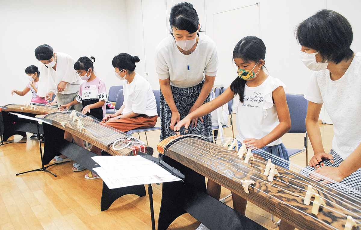 真剣な表情で初めての箏に触れる参加者