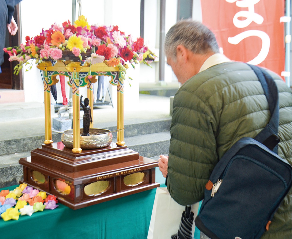 釈迦像に甘茶をかける参加者