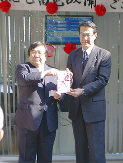 伊坂理事長（左）から目録を受け取った松森局長