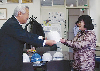ヘルメットを手渡す土志田会長（左）