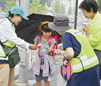 児童に折り紙の傘を渡す女性隊員