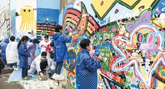 小学校の壁面に色を付けていく児童たち