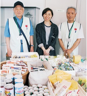 テーブルの上に並んだ提供品の前で、左から加藤理事長、小村さん、宮原事務局長