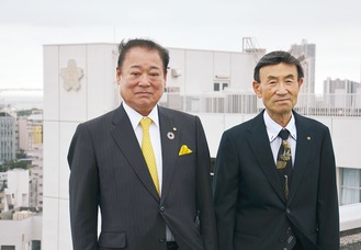校章を背に並ぶつ田中さん（左）と福島さん