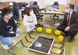 海中ソーラー発電システムを前に話し合う由井教授（写真右）と学生