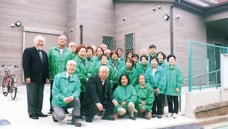 新しい会館の前で笑顔を見せる、森田会長（前列左から２人目）と町内会のメンバーら