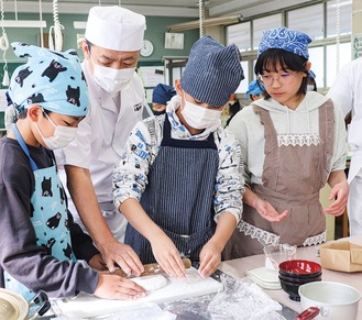 麺匠の藤本さんと一緒に生地を作る児童たち