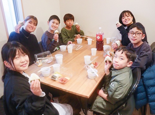 笑顔でおにぎりを食べる児童ら