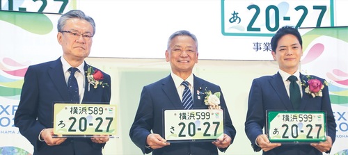 特別仕様のナンバープレートを手にする（左から）河村事務総長、高橋副大臣、山中市長