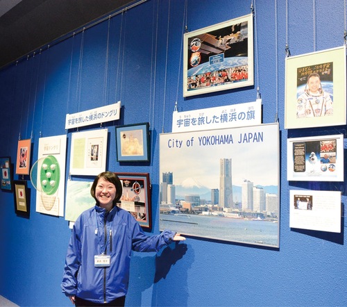 同館の鈴木さんと旗などの展示コーナー