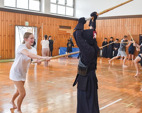 剣道着を着た部員の胴へ打ち込む参加者