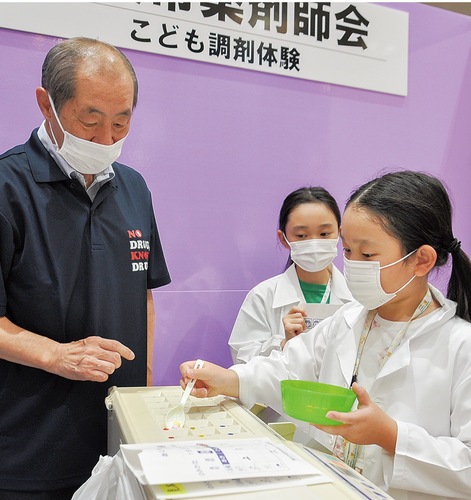 白衣を着て調剤体験を行う子どもたち