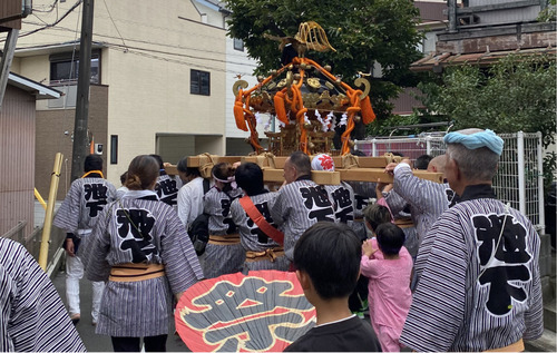 揃いの半纏で神輿を担ぐ住民ら（町会提供）