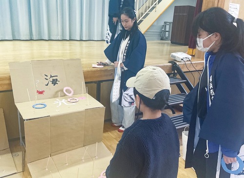 輪投げに挑戦する園児と見守る神奈川小児童たち