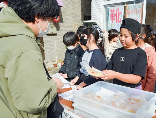 訪れた客にパンを手渡す児童