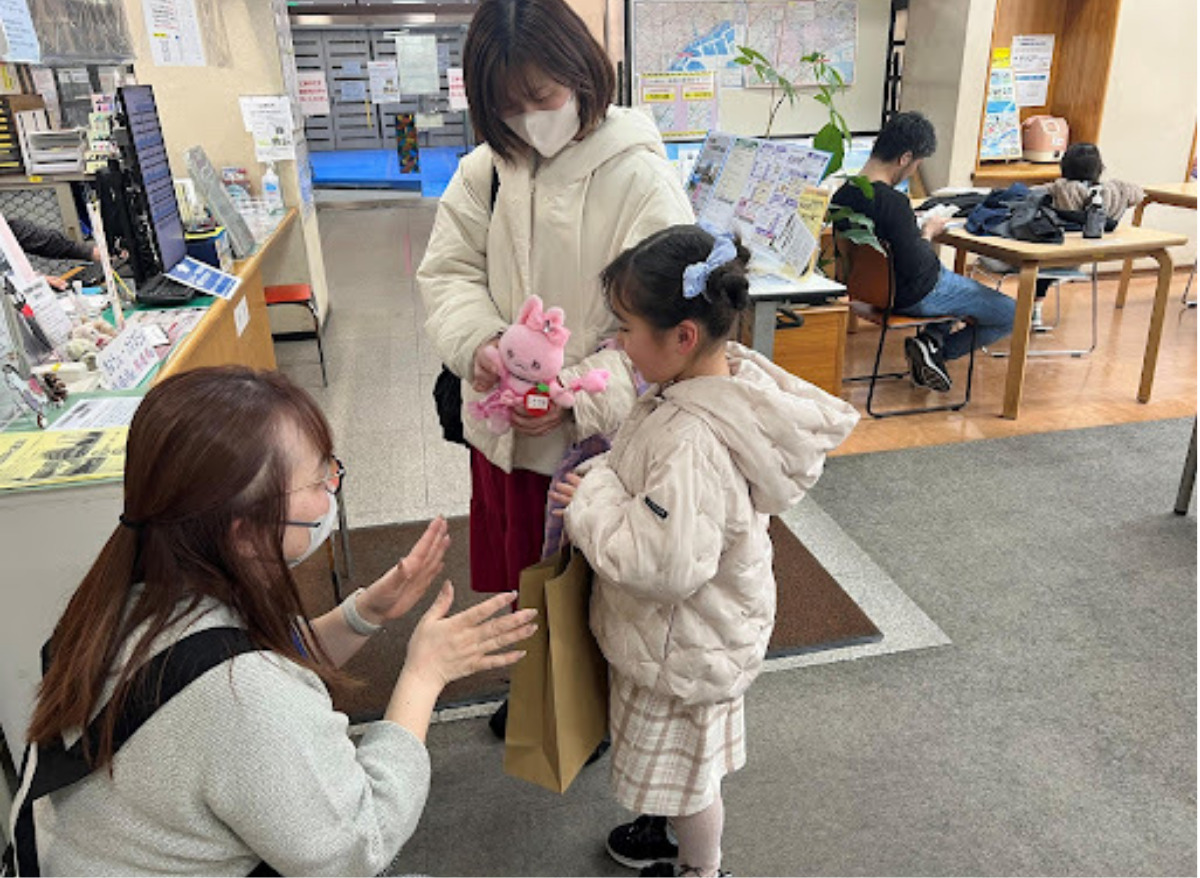 本とぬいぐるみを受け取る児童