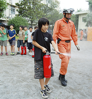 消防訓練で消火器を体験する児童