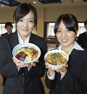 半年以上かけて開発したフィッシュ丼（右）とユッケ丼（左）を手にする学生ら