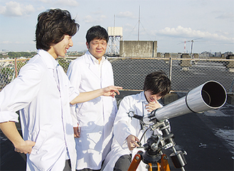 21日の本番に備え、屋上で望遠鏡の位置などを確める科学部生