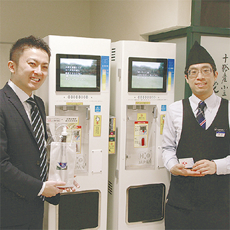 サーバーの前でＨ２‐ＢＡＧを持つ同社の小菅さん（左）と東急百貨店の末吉さん