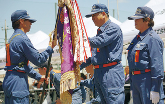 杉田団長（右）から優勝旗を受け取る馬絹班団員