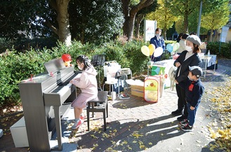 公園ピアノを弾く児童と見守る家族