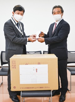 非接触型の体温計を贈る森理事（右）と高橋区長
