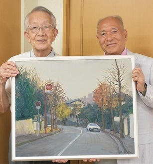 油絵を手にする筒井さん（左）と持田会長
