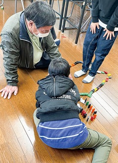 ドミノ遊びをする児童と原澄夫副会長