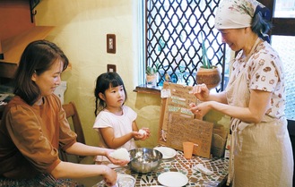 亀井さん（右）におにぎりの作り方を教わる親子