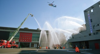 一斉放水の中、祝賀飛行する消防防災ヘリ