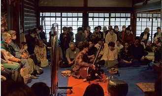 本堂でシタールを演奏する田中さん（中央）