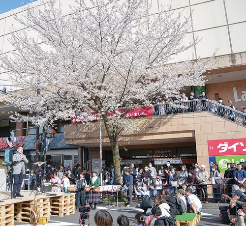 多くの人が駆け付けたフレル前道路の特設ステージであいさつする齋藤区長